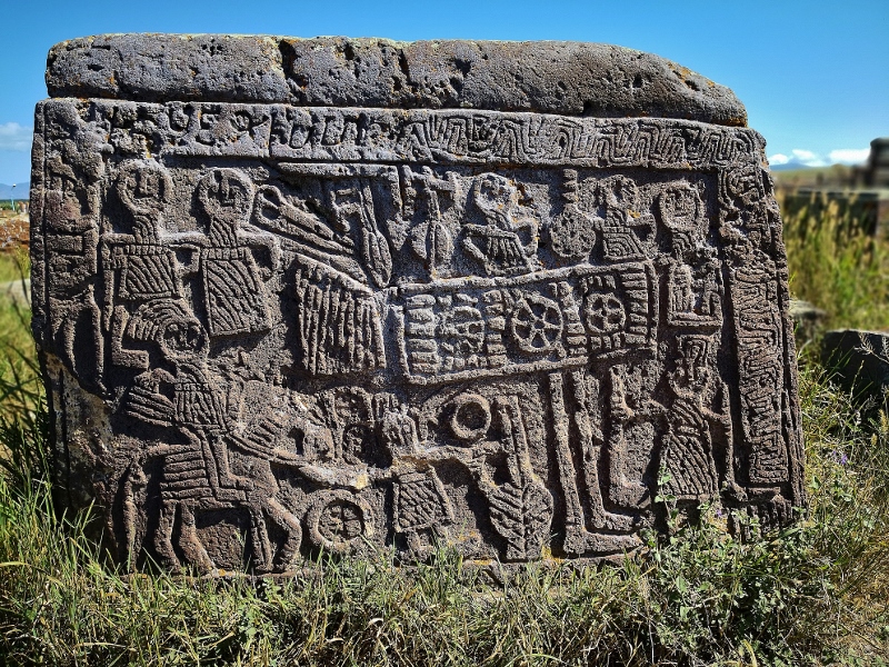 Die Steine erzählen ganze Geschichten. Wir sehen einen Mann und eine Frau, eine Schere und andere Werkzeuge, Kinder und einen Tisch mit Lavasch, dem armenischen Brot, einen Weinkrug und links unten im Bild einen Mongolen auf seinem Pferd, der die Familie im 13. Jahrhundert umgebracht hat